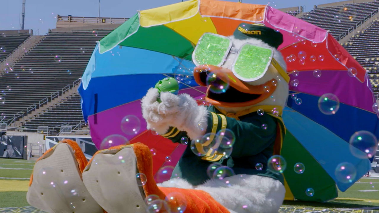 Photo of duck under rainbow umbrella and blowing bubbles