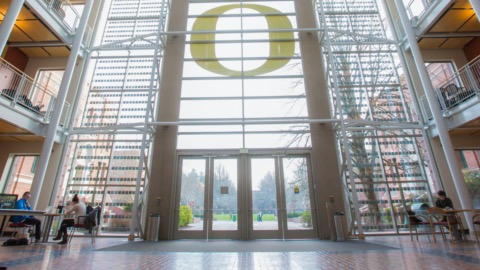 View looking out at the front of a glass wall with the O logo above the doors